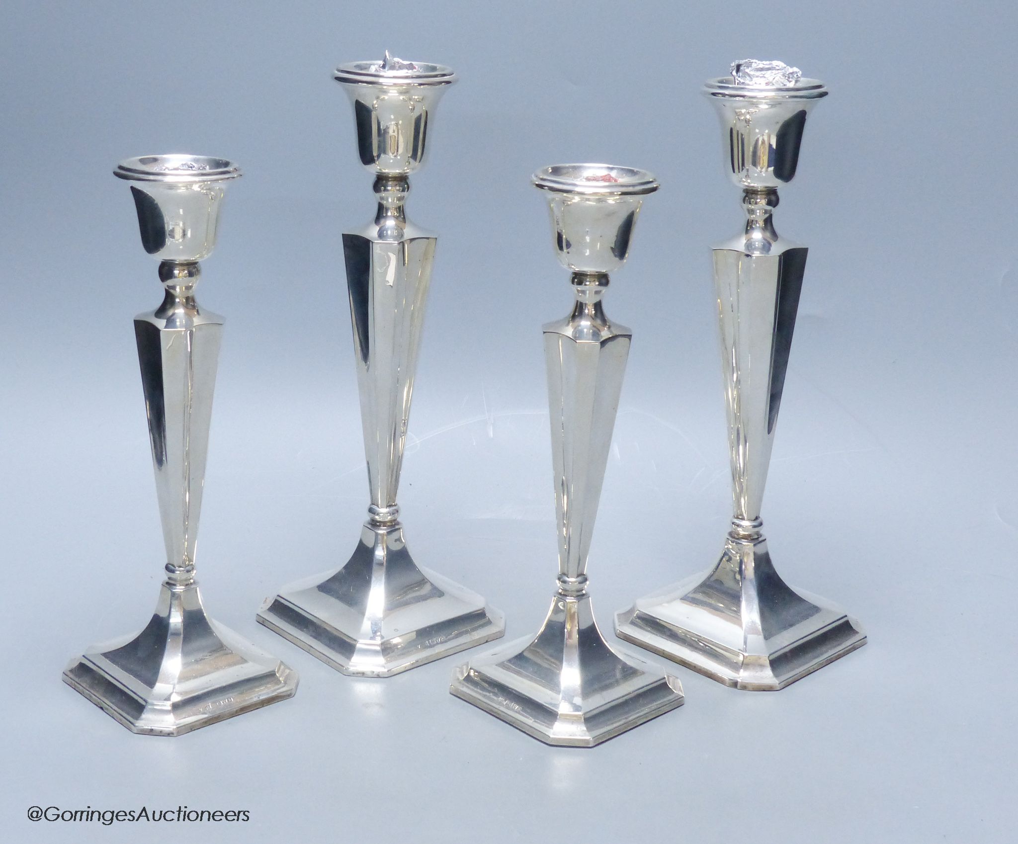 Two graduating pairs of George V silver candlesticks, James Deakin & Sons, Chester, 1925, weighted, tallest 26.1cm.